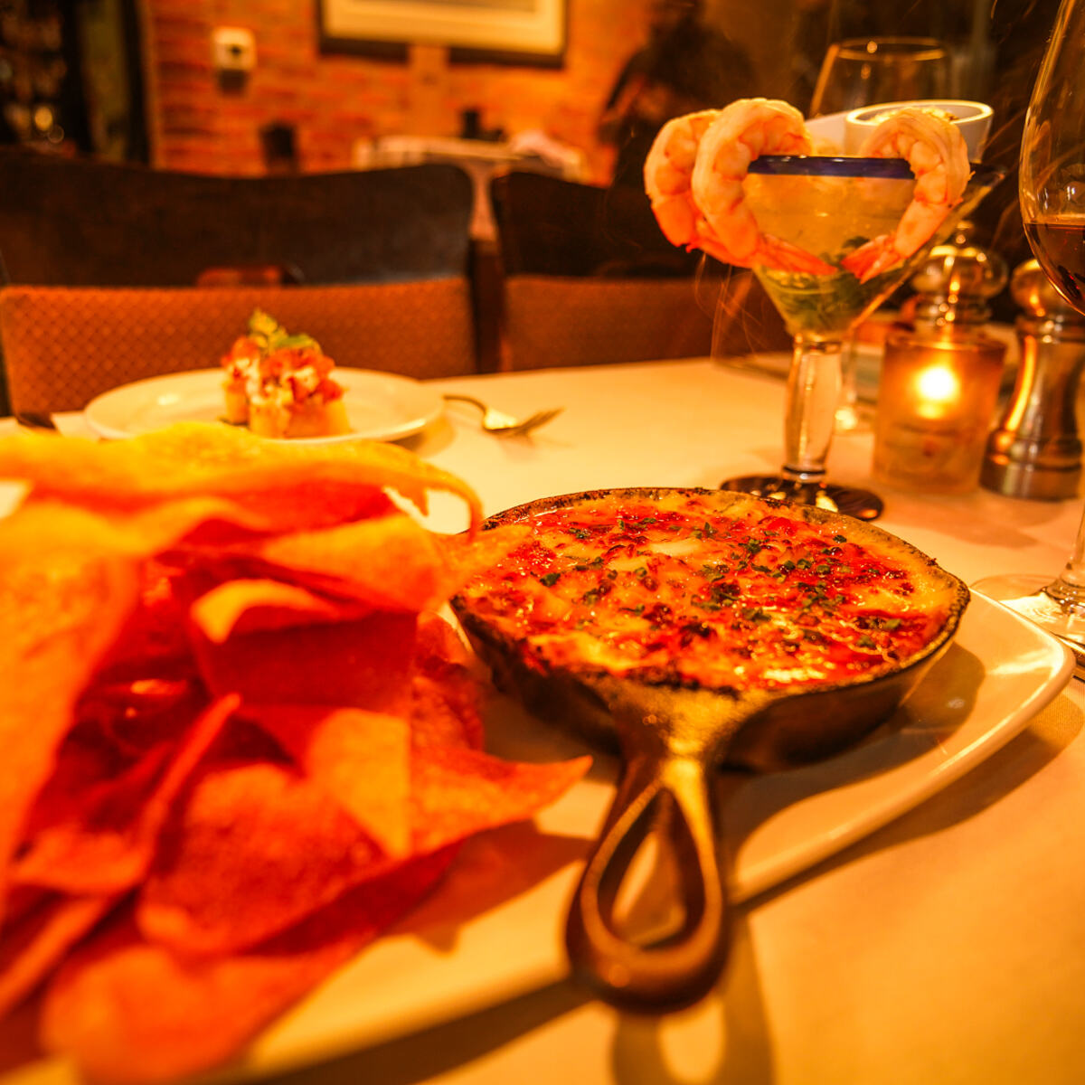 A skillet of crab dip with chips at the table