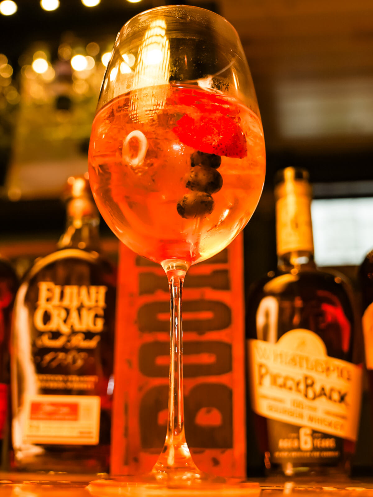 A tall pour at the bar with bottles behind